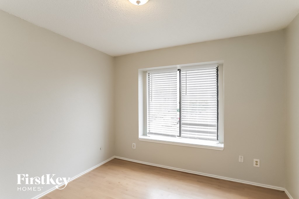 a bedroom with a large window and wooden floors