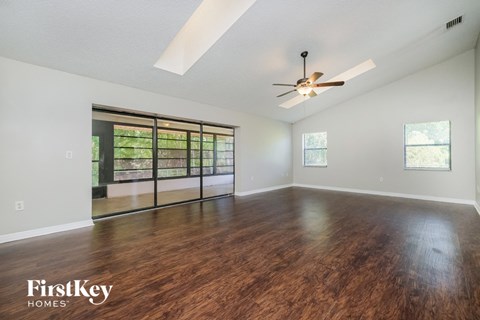 A spacious room with wooden floors and a ceiling fan.