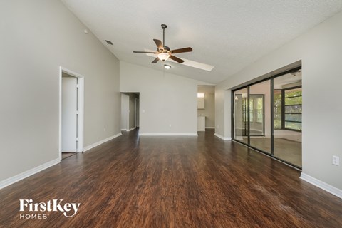 A spacious room with wooden floors and a ceiling fan.