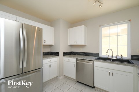 A kitchen with a stainless steel refrigerator and white cabinets.
