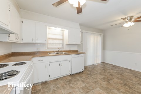 A kitchen with white cabinets and a tiled floor.