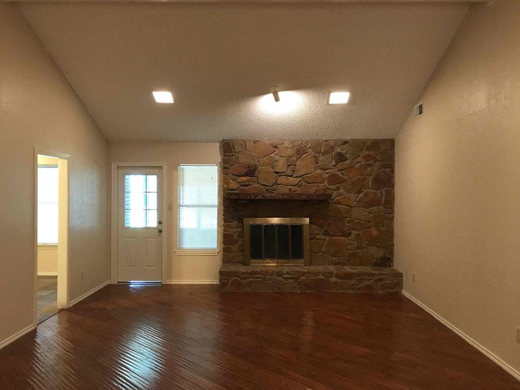 a living room with a stone fireplace and wooden floors
