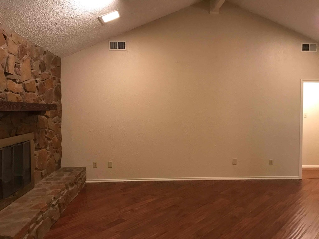 a living room with a stone fireplace and wooden floors