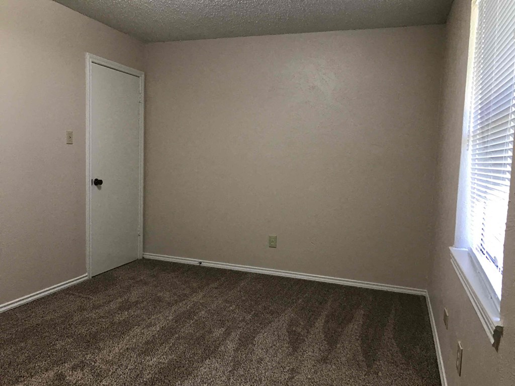 a room with a carpeted floor and a window and a door