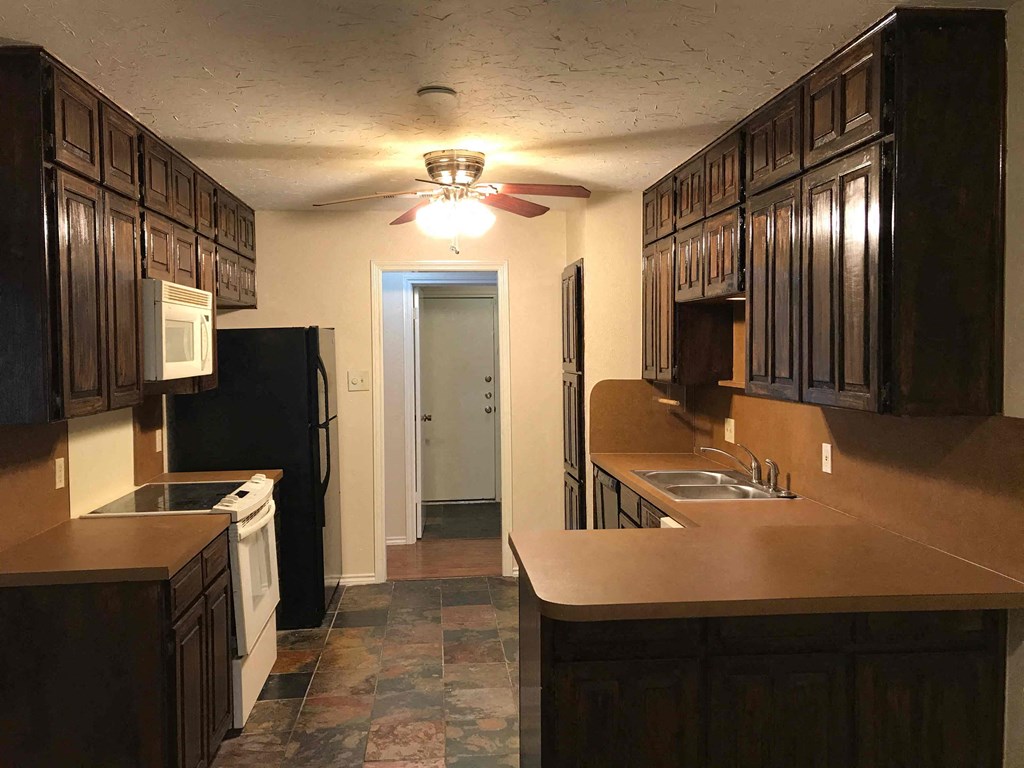 a kitchen with a sink and a refrigerator and a ceiling fan
