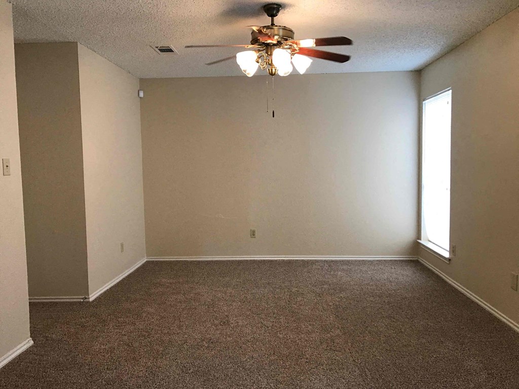 an empty living room with a ceiling fan