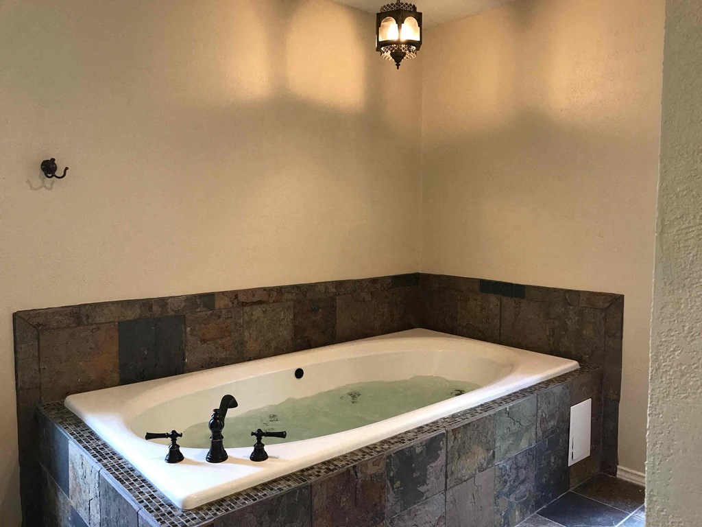 a large jacuzzi tub in a bathroom with a light above it