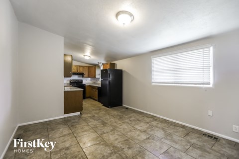 A kitchen area with a black refrigerator and a tiled floor.