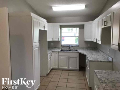 A kitchen with white cabinets and a marble countertop.
