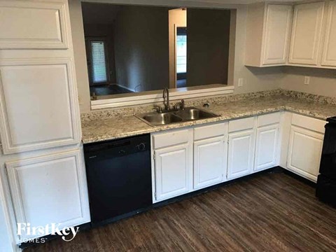 A kitchen with white cabinets and a black dishwasher.