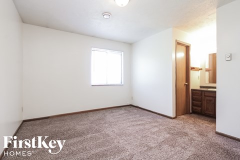 the living room of a small white house with carpet and a window