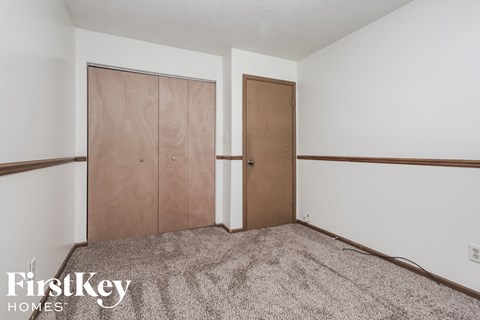 a bedroom with a carpeted floor and two closet doors