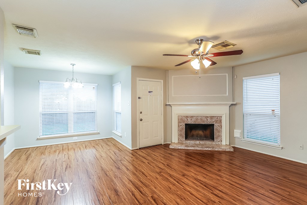 A spacious living room with a fireplace and wooden floors.