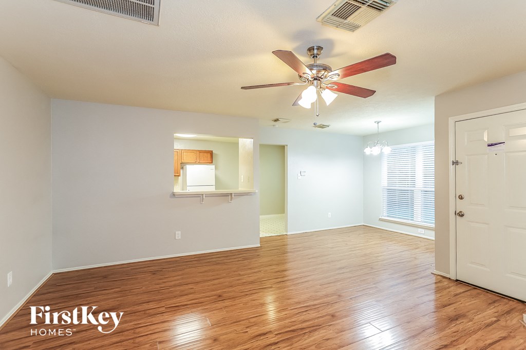 A room with a ceiling fan and wooden floors.