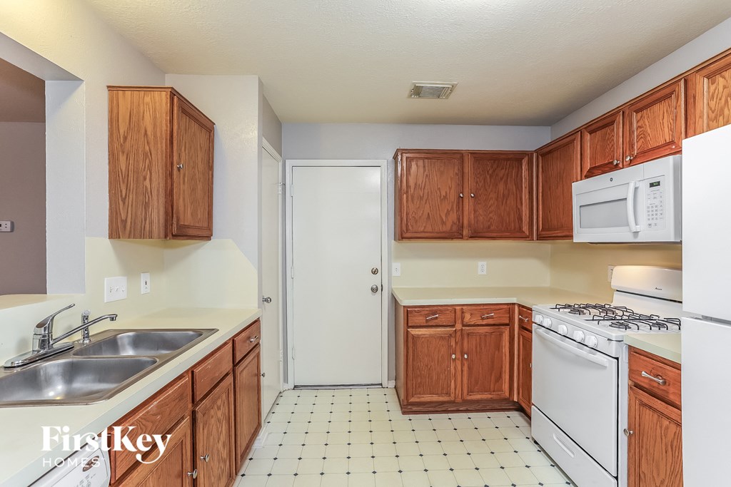 A kitchen with white appliances and wooden cabinets.