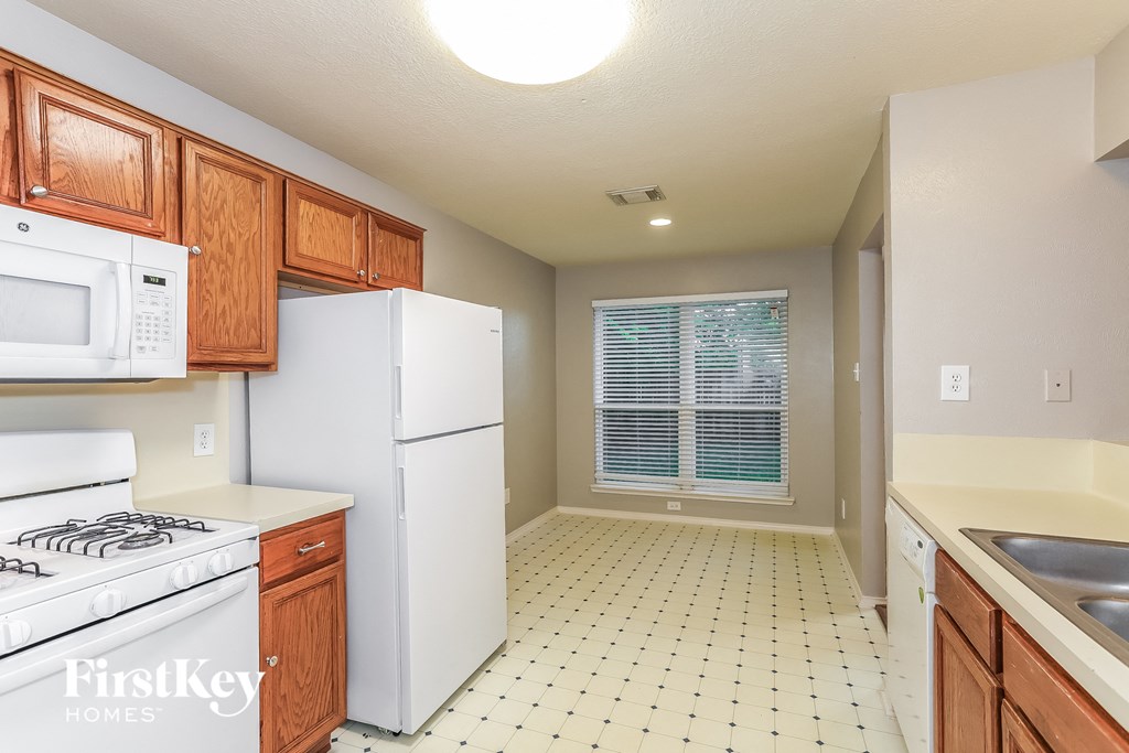 A kitchen with a white refrigerator, white stove, and wooden cabinets.