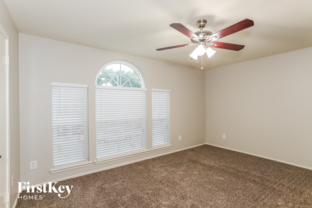 A room with a ceiling fan and a window with blinds.