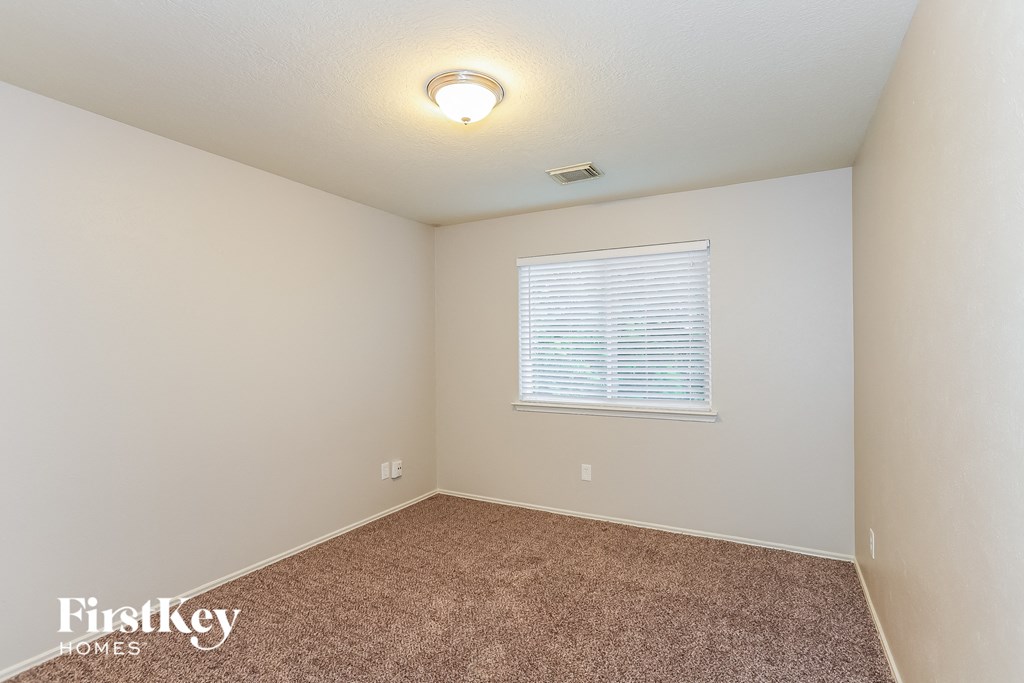 A room with a carpeted floor and a window with blinds.