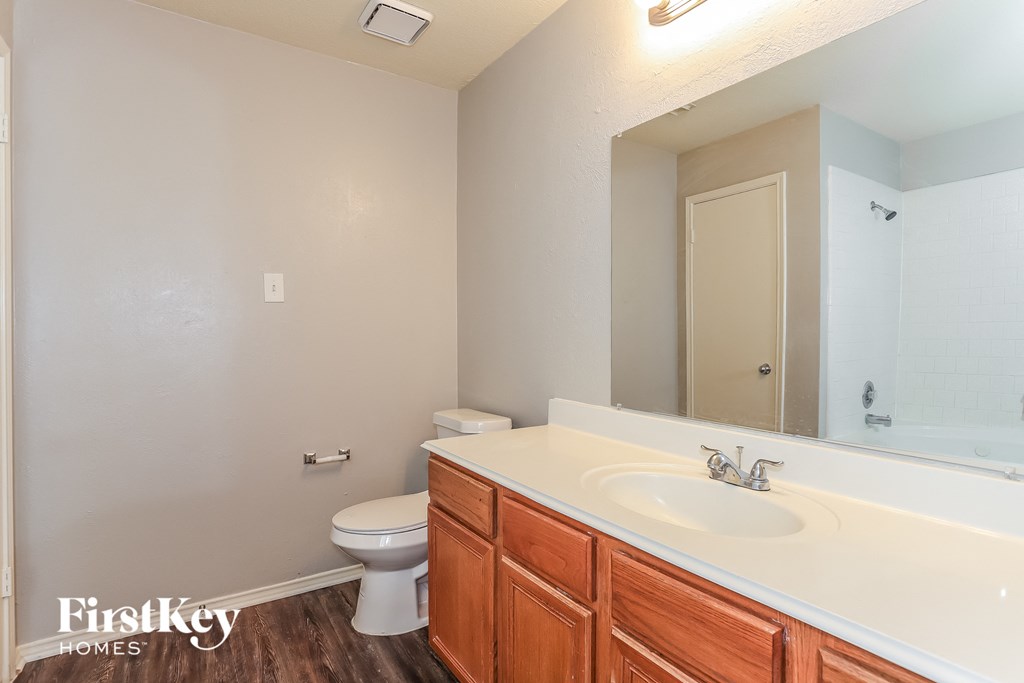 A bathroom with a toilet, sink, and mirror.
