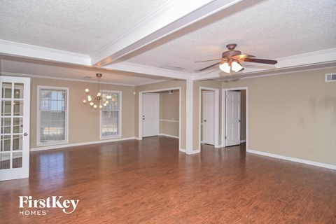 an empty living room with wood floors and a ceiling fan