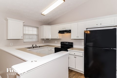 a kitchen with white cabinets and a black refrigerator