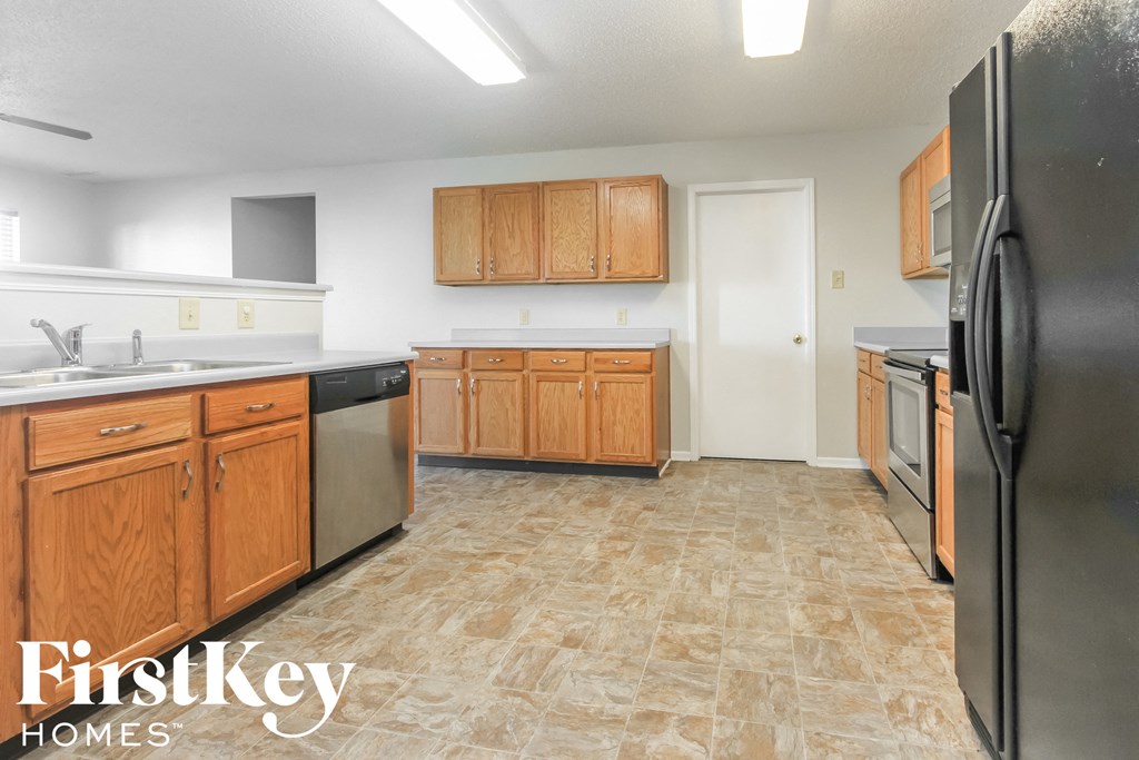 A kitchen with wooden cabinets and a black refrigerator.
