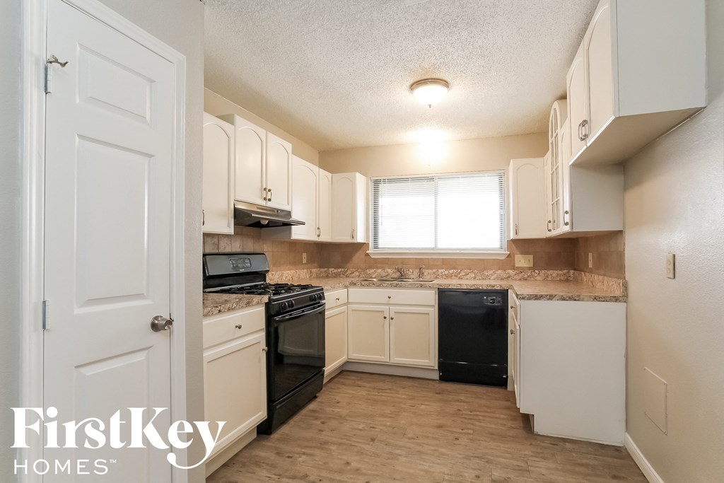 a kitchen with white cabinets and black appliances and a window