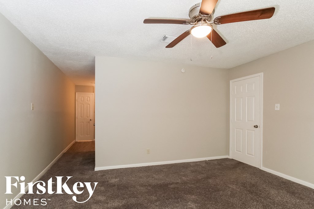 the spacious living room with ceiling fan and carpet