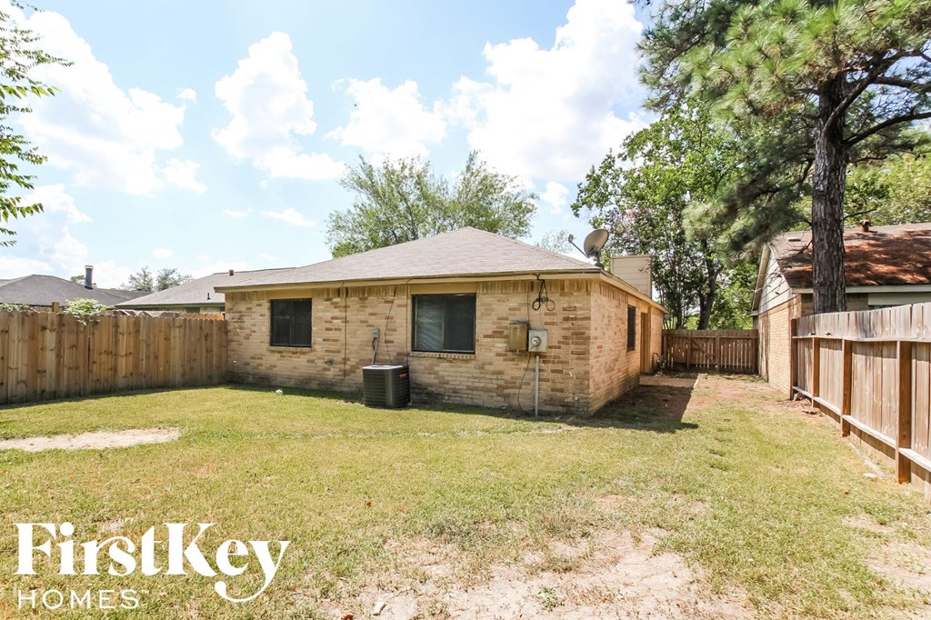 a small brick house with a backyard and a fence