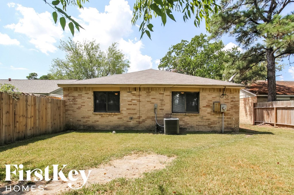 a small brick house in a backyard with a wood fence