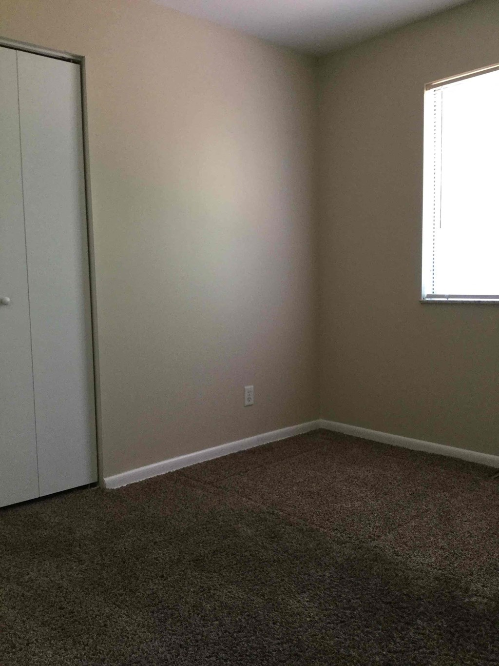 A room with a carpeted floor and a white door.