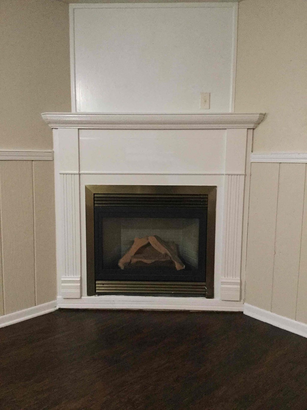 A fireplace with a white mantle and a fire burning inside.