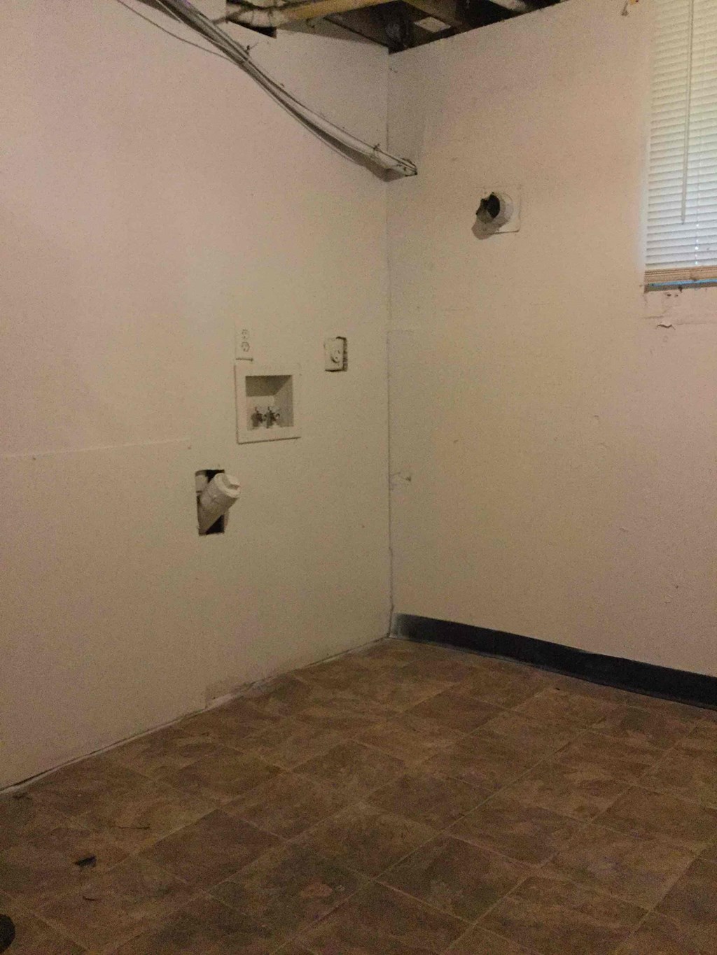 A room with a tiled floor and a window with blinds.