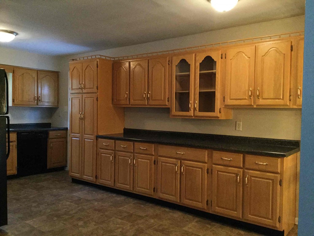 A kitchen with wooden cabinets and black countertops.
