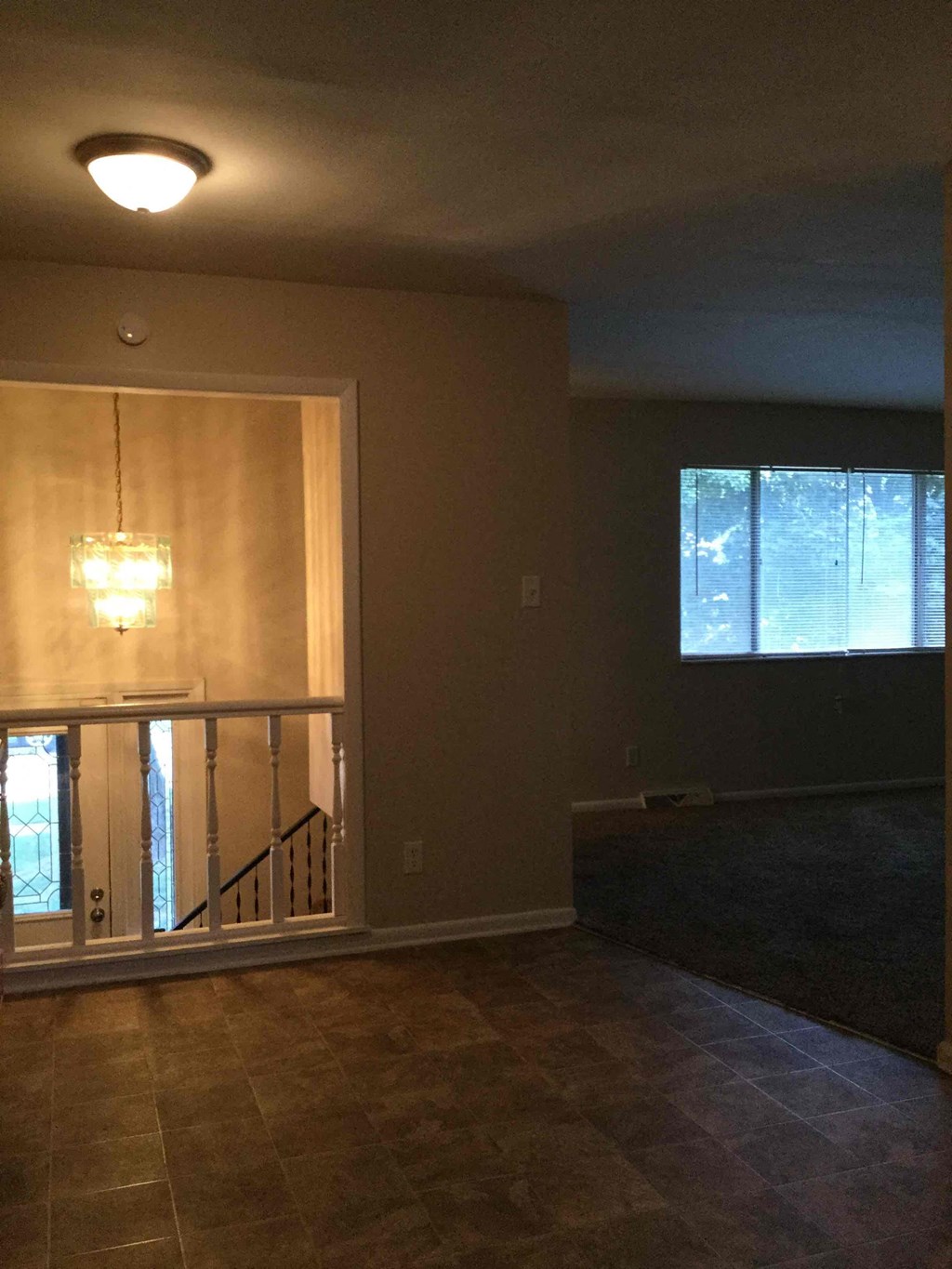 A room with a light on the ceiling and a window with a view of trees outside.
