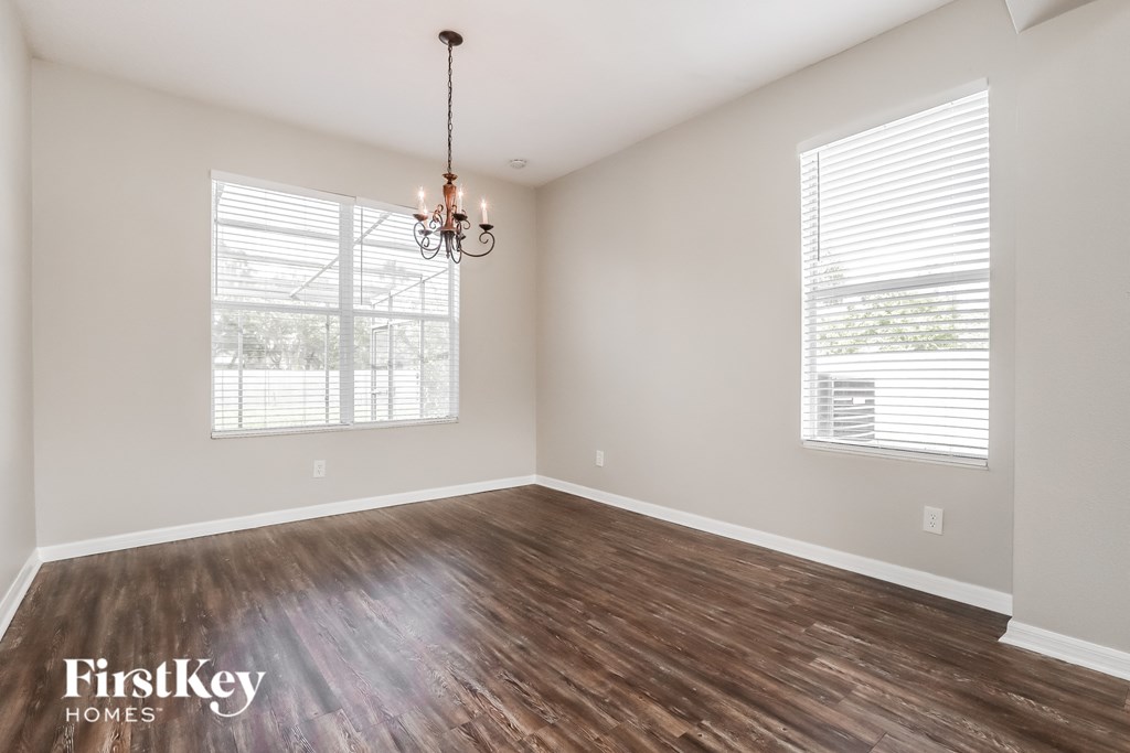 an empty living room with wood floors and a chandelier