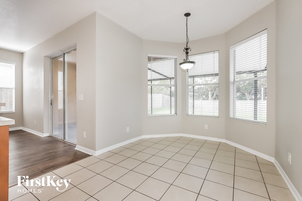 an empty living room with windows and a door to the kitchen