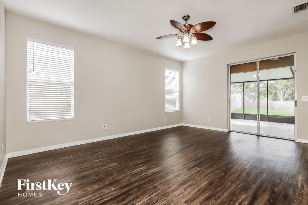 an empty living room with a ceiling fan and a sliding glass door