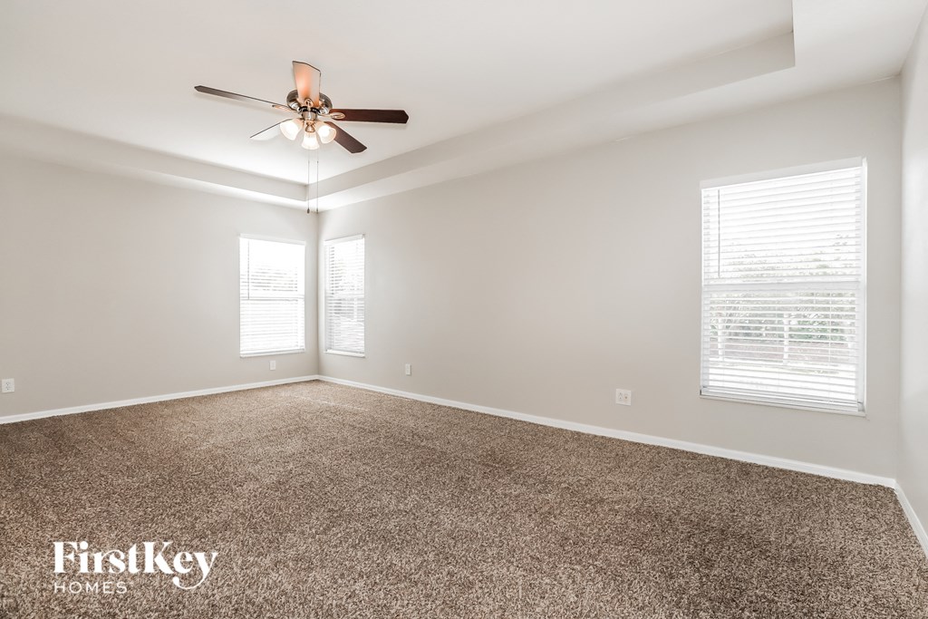 a living room with a ceiling fan and a carpet