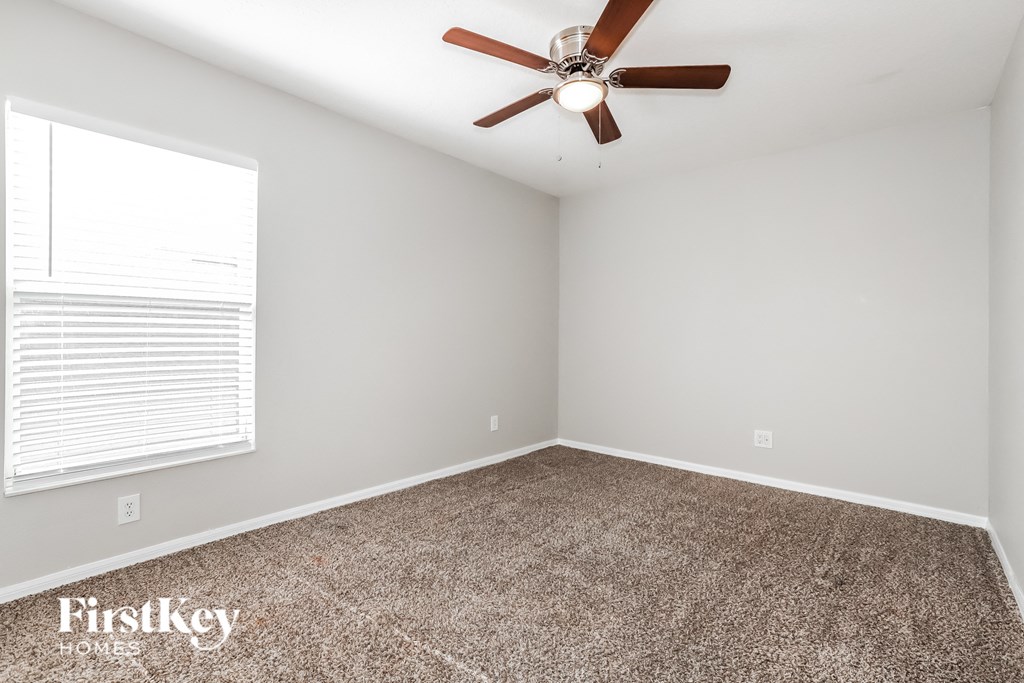 an empty room with a ceiling fan and a window