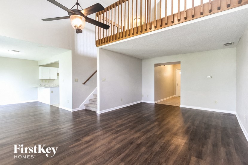 an empty living room with wood floors and a ceiling fan