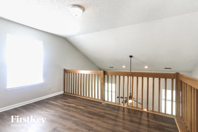a loft with wood floors and white walls and a window