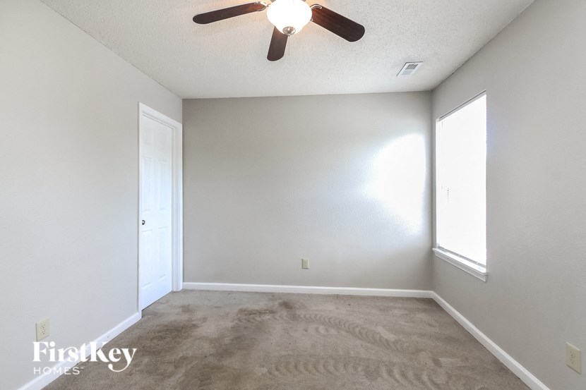 a empty living room with carpet and a ceiling fan