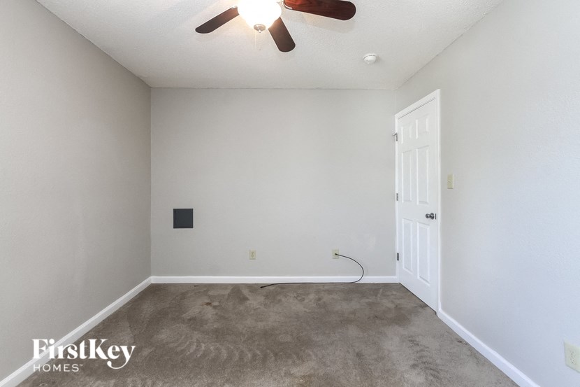 a empty living room with white walls and a ceiling fan