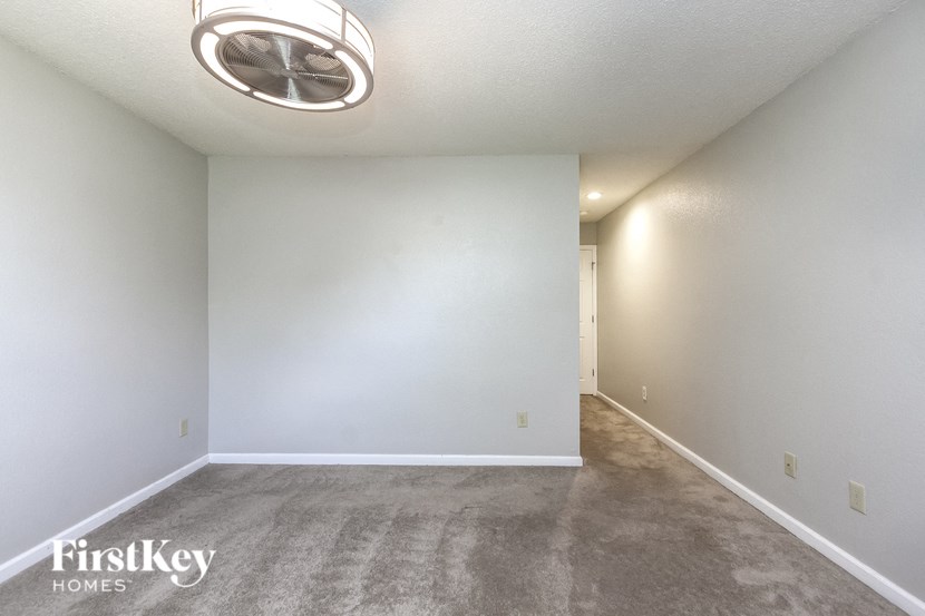 an empty living room with carpet and a ceiling fan