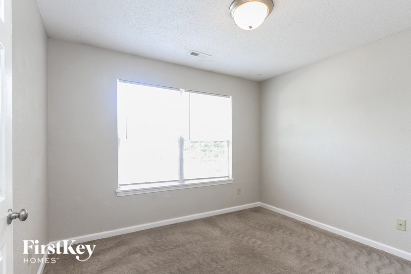 a bedroom with a large window and a carpeted floor