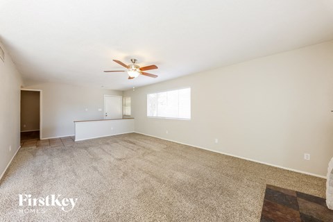 a spacious living room with carpet and a ceiling fan