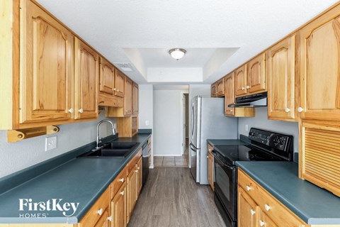 a kitchen with wood cabinets and black counter tops and a black stove and refrigerator