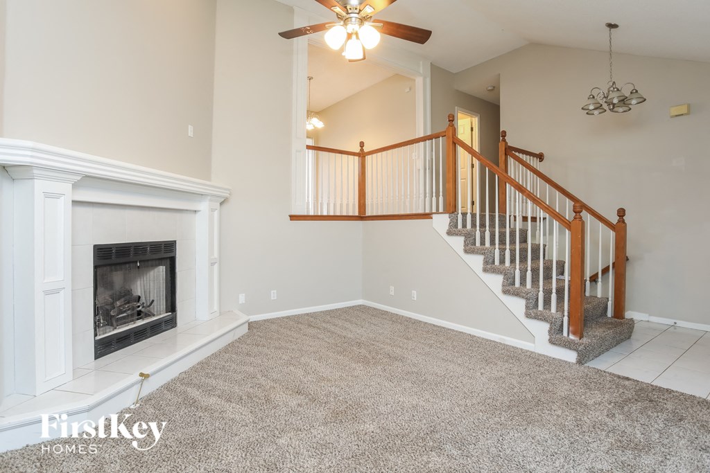 A spacious living room with a fireplace and a staircase.
