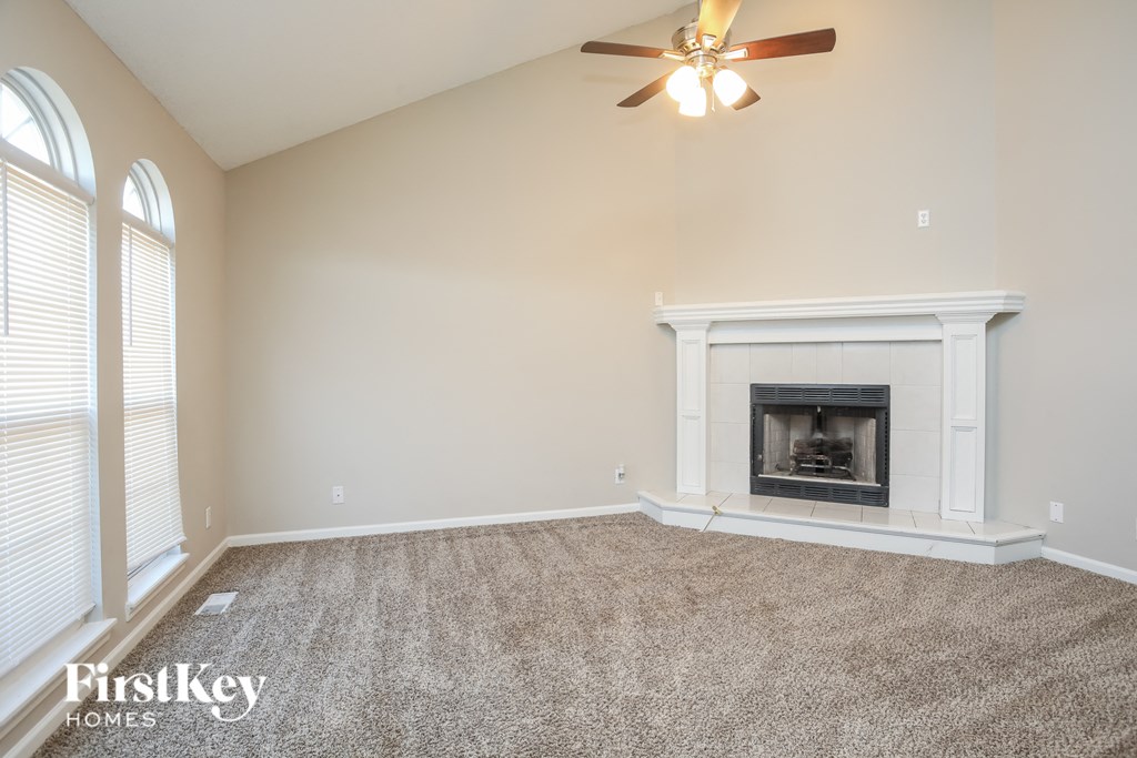 A living room with a fireplace and a ceiling fan.